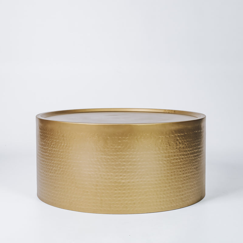 An elegant hammered brass side table, reflecting warm ambient light