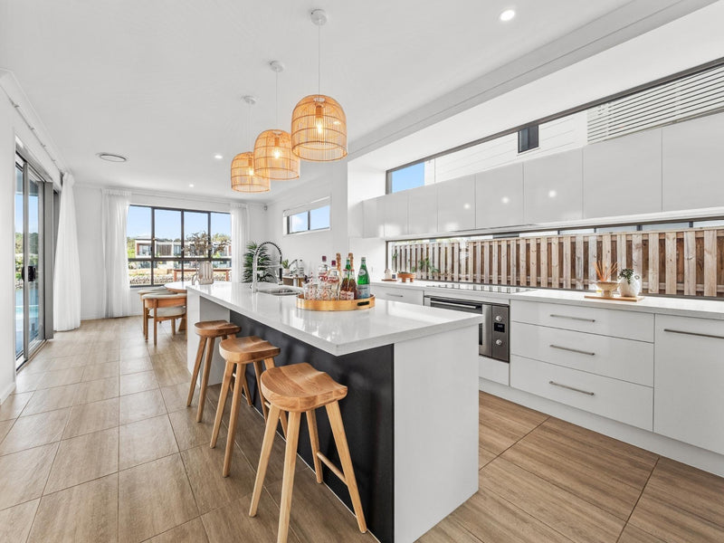 large rattan pendant light in a white kitchen with timber barstools