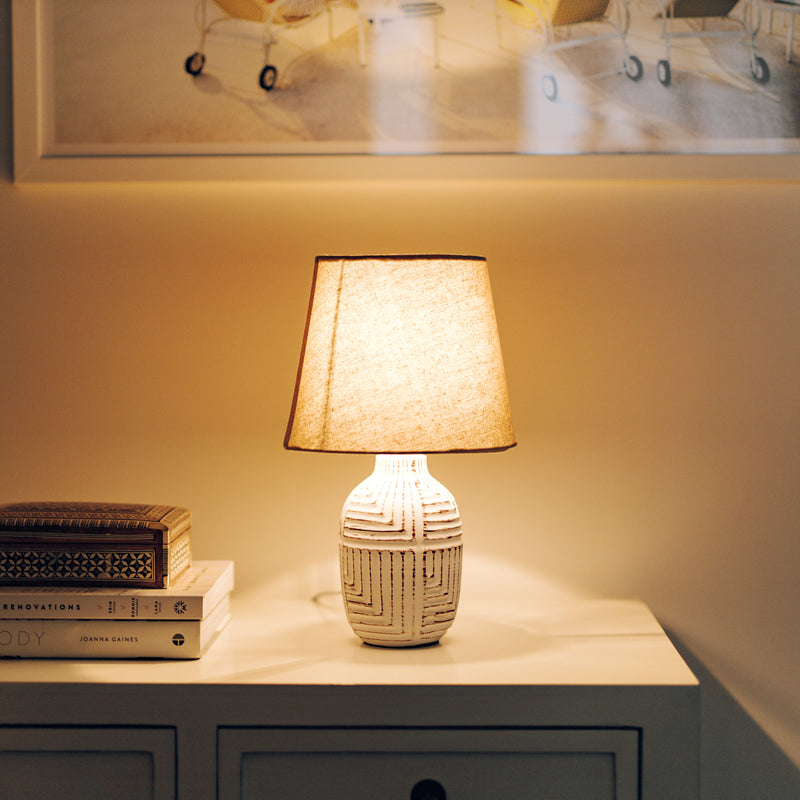 Kai table lamp with natural linen shade, turned on.