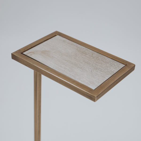 A minimalist gold side table with a thin, vertical support and an open rectangular base, featuring a sleek, modern design.