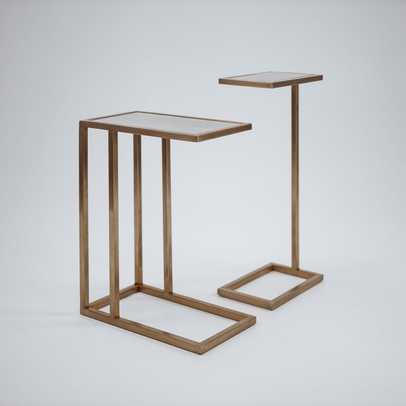 A minimalist gold side table with a thin, vertical support and an open rectangular base, featuring a sleek, modern design.