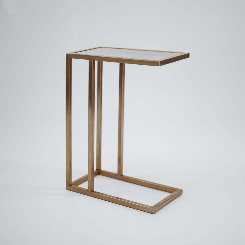 A minimalist gold C-shaped side table with a sleek, modern design, featuring a flat rectangular top and an open base.
