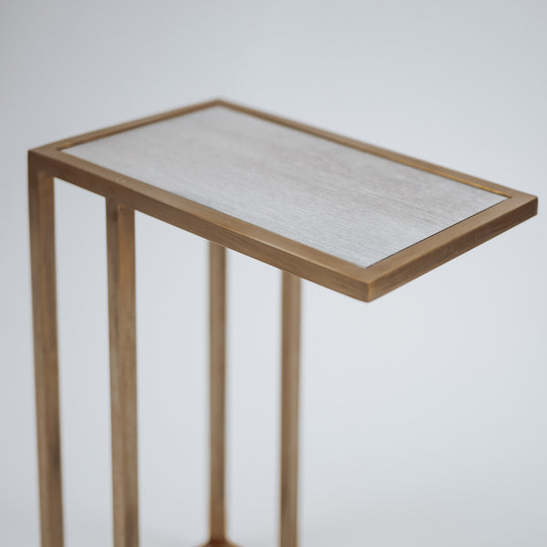A minimalist gold C-shaped side table with a sleek, modern design, featuring a flat rectangular top and an open base.