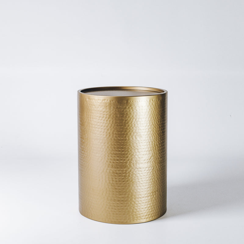 An elegant hammered brass side table, reflecting warm ambient light.