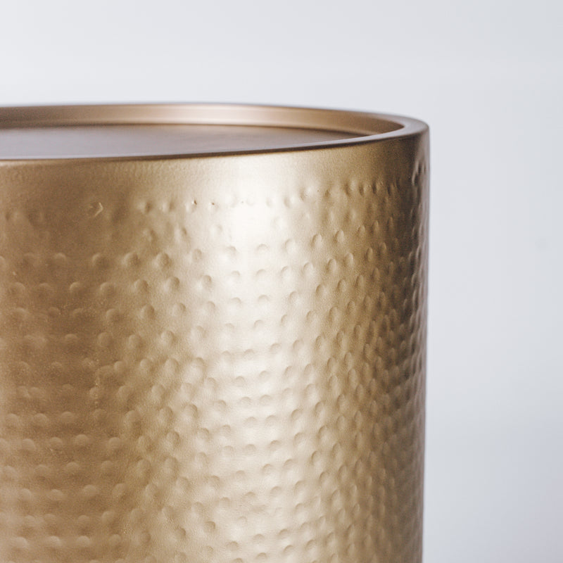 An elegant hammered brass side table, reflecting warm ambient light.