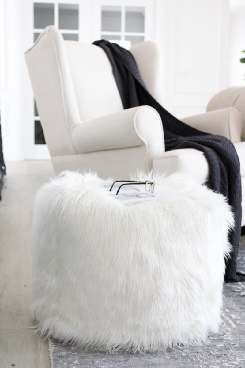 white fur ottoman next to a luxury occasional chair on a large floor rug
