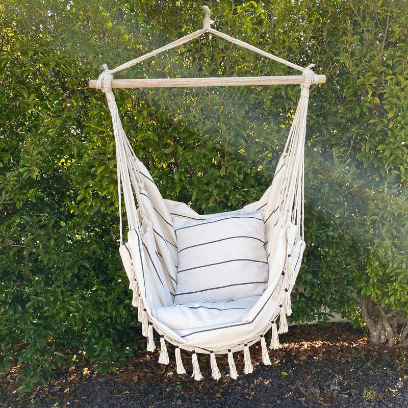 hanging hammock chair with pinstripe pattern and comes with matching cushions hanging out in the garden