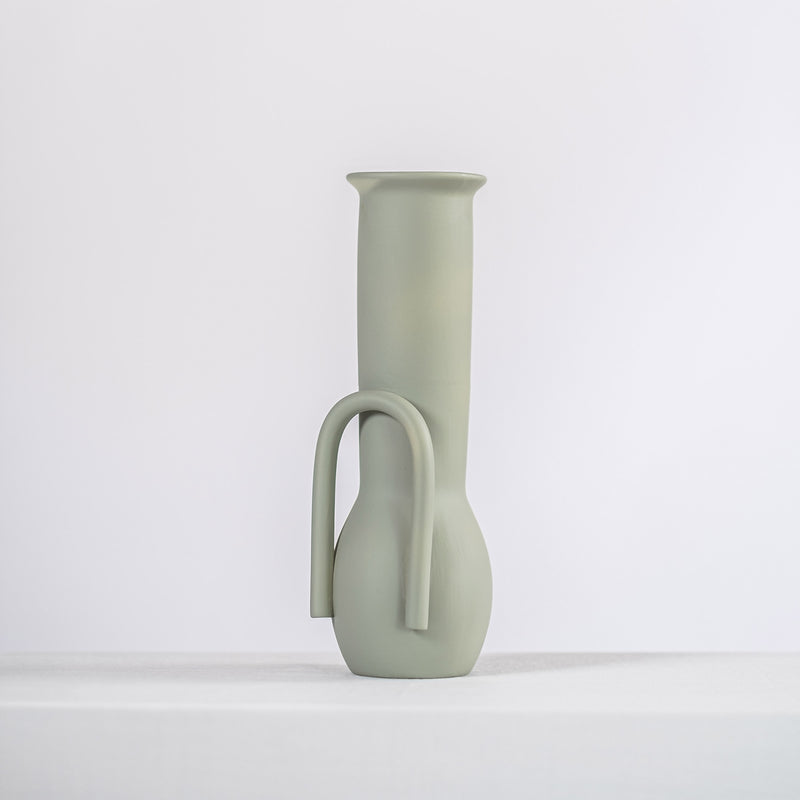 sage ceramic vase on a white shelf