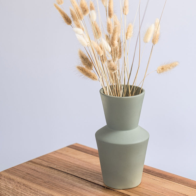 modern sage ceramic vase on a wooden shelf with dried flowers