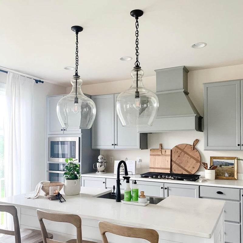 large glass pendant light with black hardware over a kitchen island