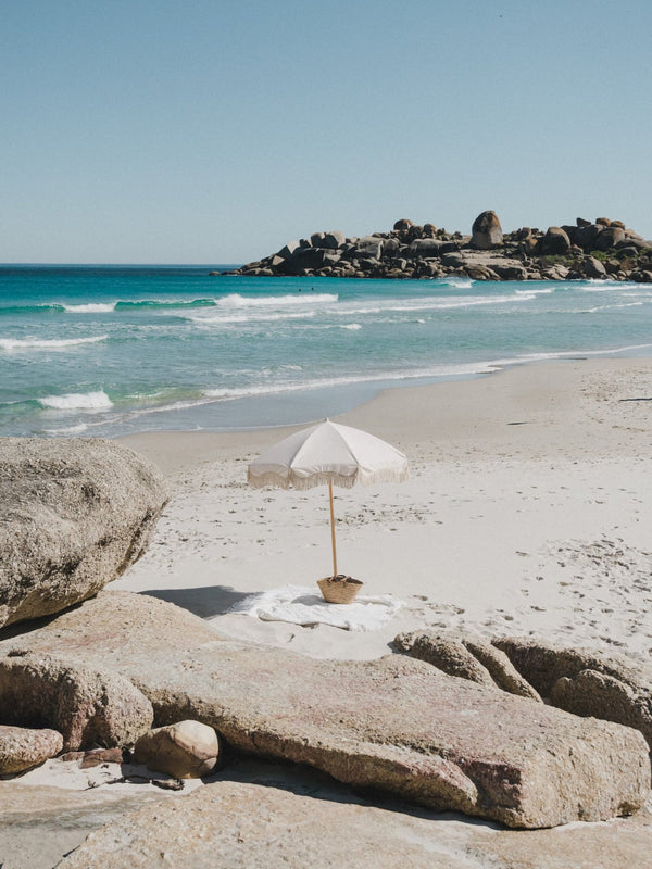 bora bora beach umbrella with fringe on a sandy beach by the ocean