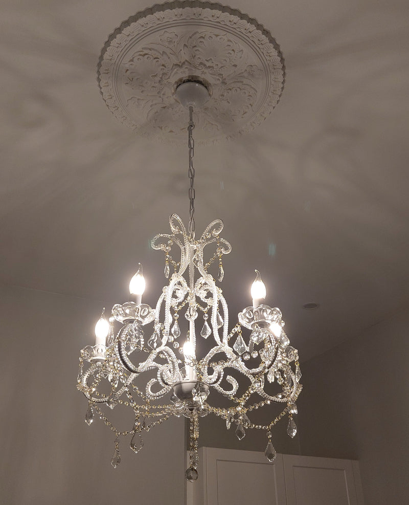 chandelier hanging in a bedroom with an ornate ceiling rose