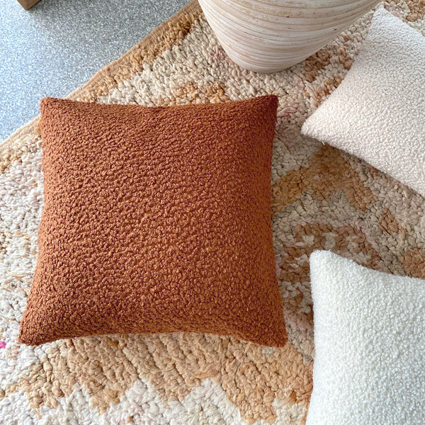 Rust Boucle Cushion: A warm and textured cushion featuring boucle fabric in a rich rust color, perfect for adding rustic elegance, warmth, and style to any seating or bedding arrangement.