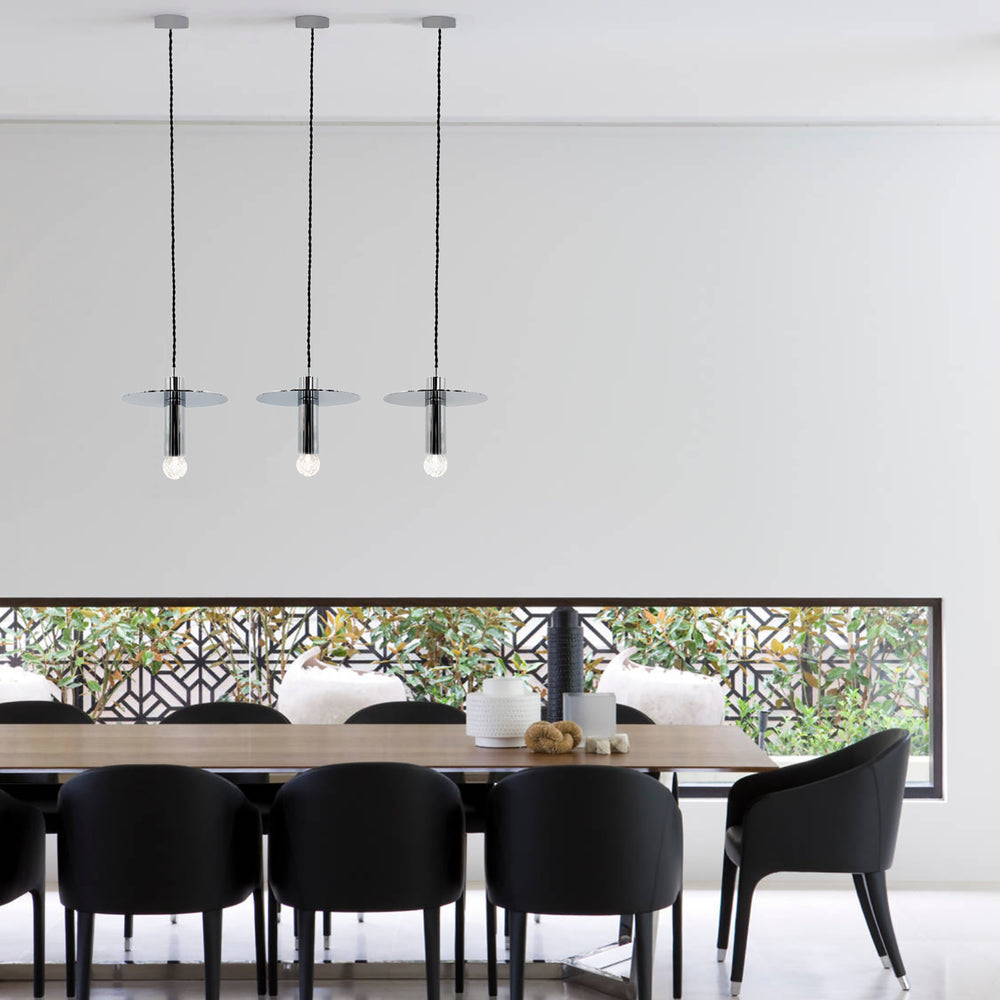 modern chrome pendant light hanging over a dining table