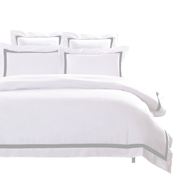 A soft white quilt cover on a neatly made bed with pillows in a modern bedroom setting