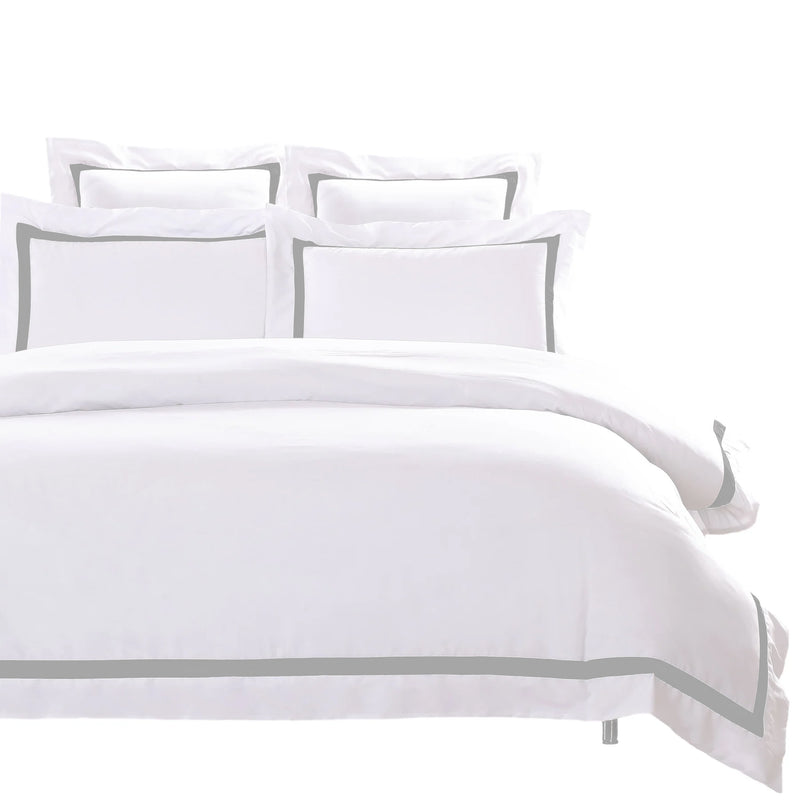 A soft white quilt cover on a neatly made bed with pillows in a modern bedroom setting
