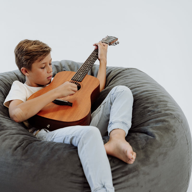boy playing guitar in a fur bean bag